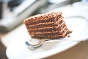 A slice of chocolate cake on a white plate with a spoon