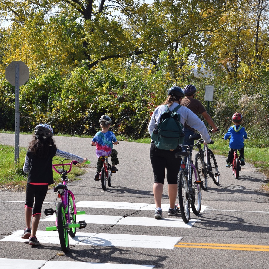 In this bike photo the family has gathered together at a busy intersection to cross on their way to the local fair.