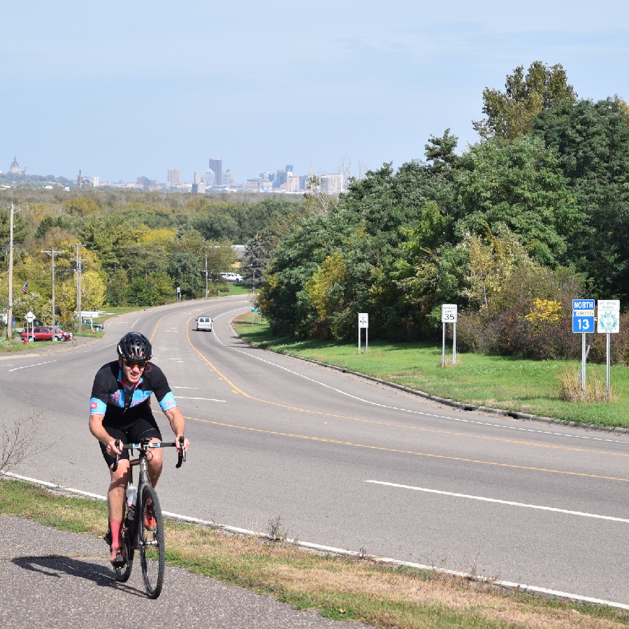 A bike rider riding along the Mississippi River Trail, in Mendota Heights, with the Downtown St. Paul skyline in the background. 