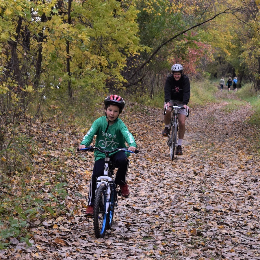 A boy riding in the woods with family