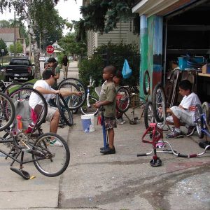 Discovering how things work here is a group of neighborhood kids learning about bicycle maintenance. 