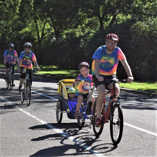 In this bike pic, this family knows where the shaded lanes are in St. Paul, MN to stay cool. Dressed in matching tie-dyed T-shirts this family know that riding along Summit Avenue offers protection from the hot sun. 
