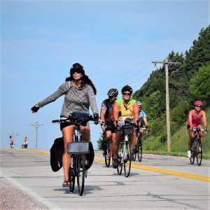 Here in this bike pic, we captured a self-sufficient biker chick having fun pedaling into the Monday morning sun with a solar panel mounted to the front of her bike while riding across Iowa.