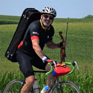 This Bike Pic Friday, digging through the summer archives we found this biker dude with a fiddle in hand enjoying the Iowa countryside, on the ride across Iowa, RAGBRAI.